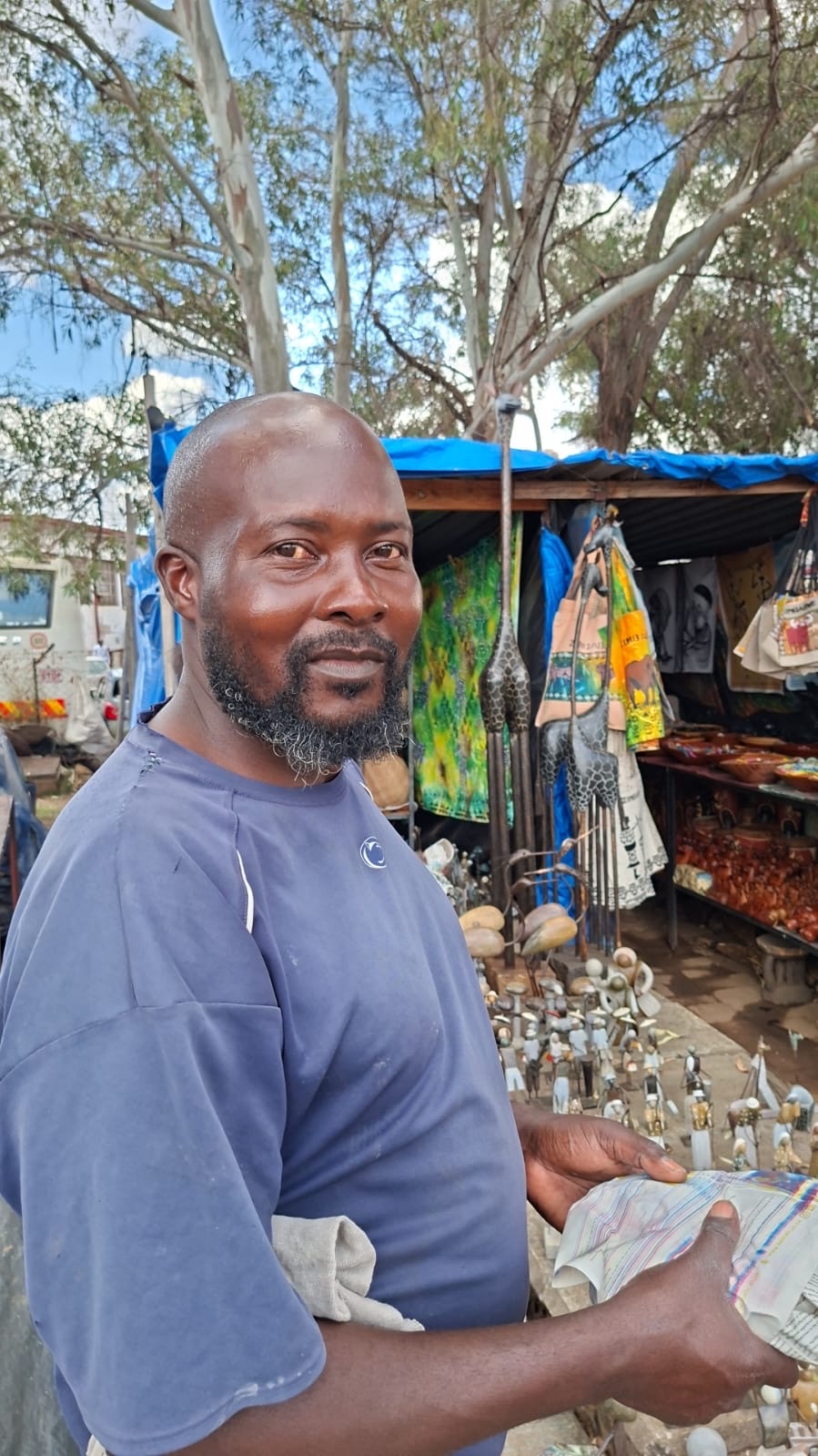 Artisan standing at his market stall surrounded by handcrafted goods