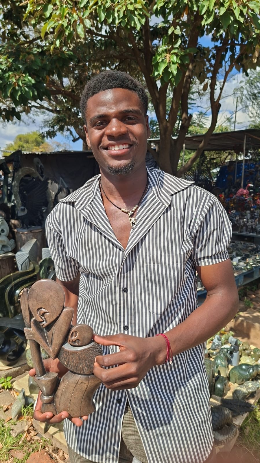 Smiling young sculptor holding a finished stone figure